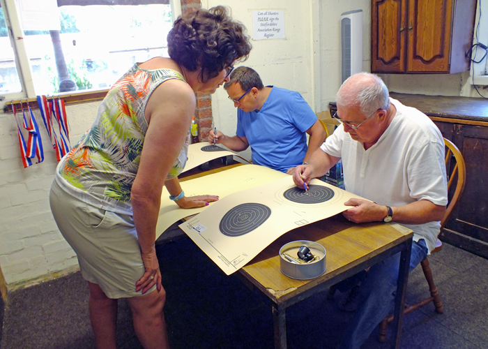 Photograph shows the Official Scorers keenly assessing the shot targets.