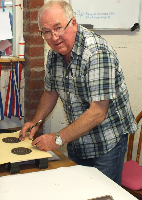 Photograph shows Fred Dukes diligently scoring the shot targets.